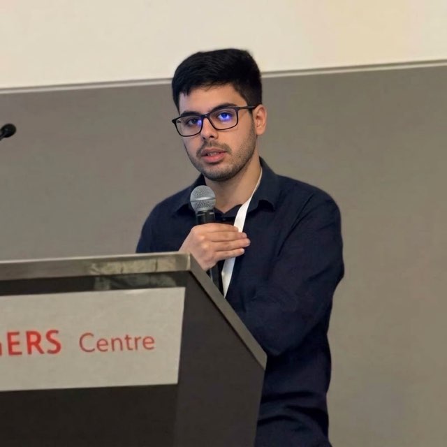 Matheus Leca speaking into a microphone at a podium